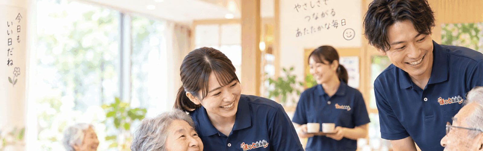 ほっと倶楽部の求人メインビジュアル。スタッフと入居者様が笑顔で交流している様子